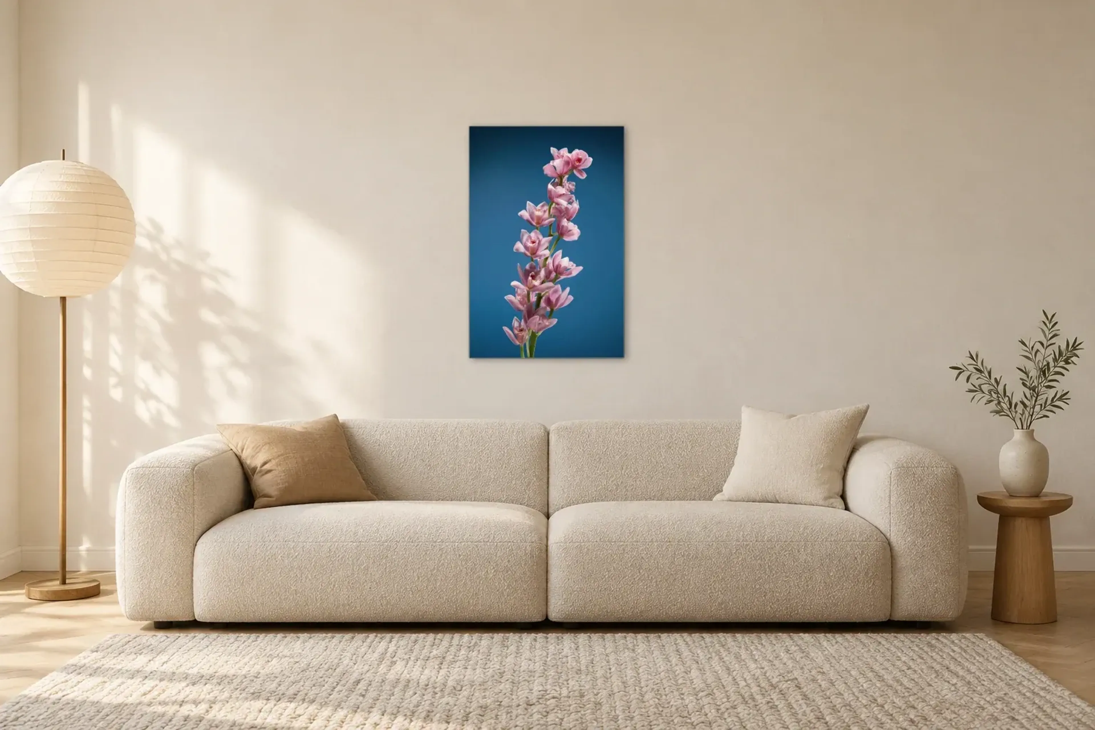 Rosa Orchideen vor Blau als Wandbild über einem 230-cm-Sofa