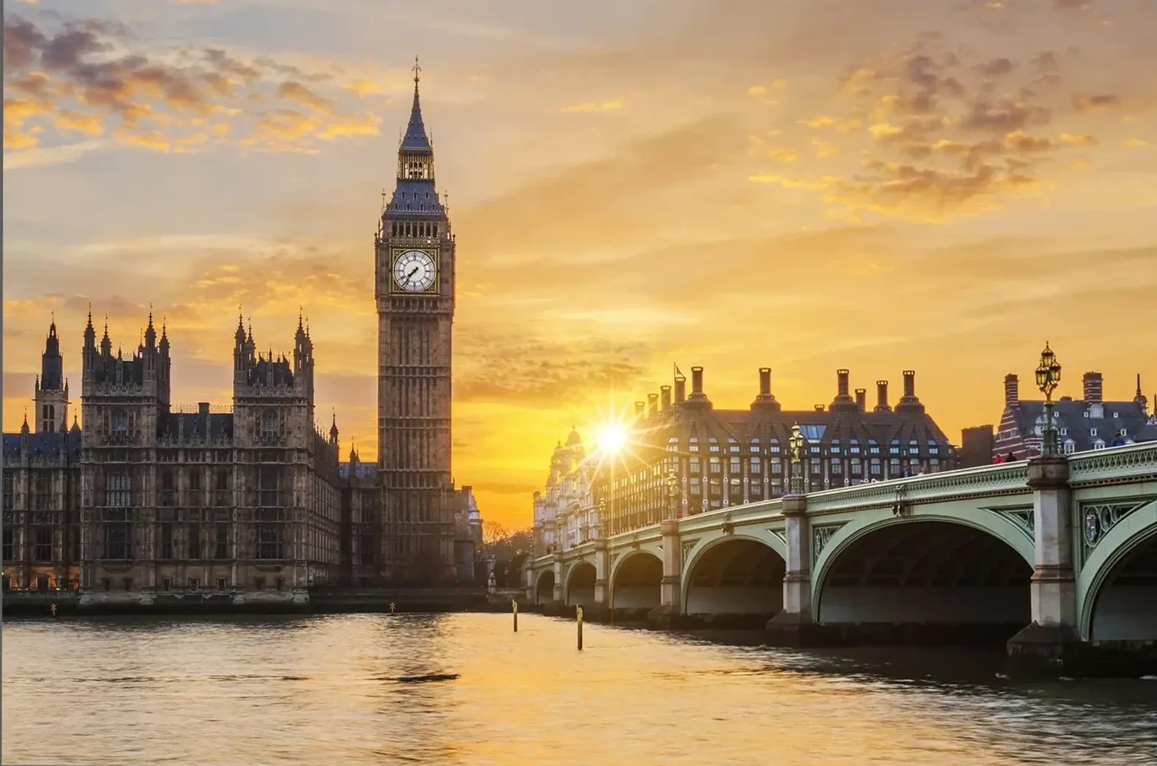 Big Ben, Parlament und Westminster Bridge an der Themse im goldenen Licht der tief stehenden Sonne.