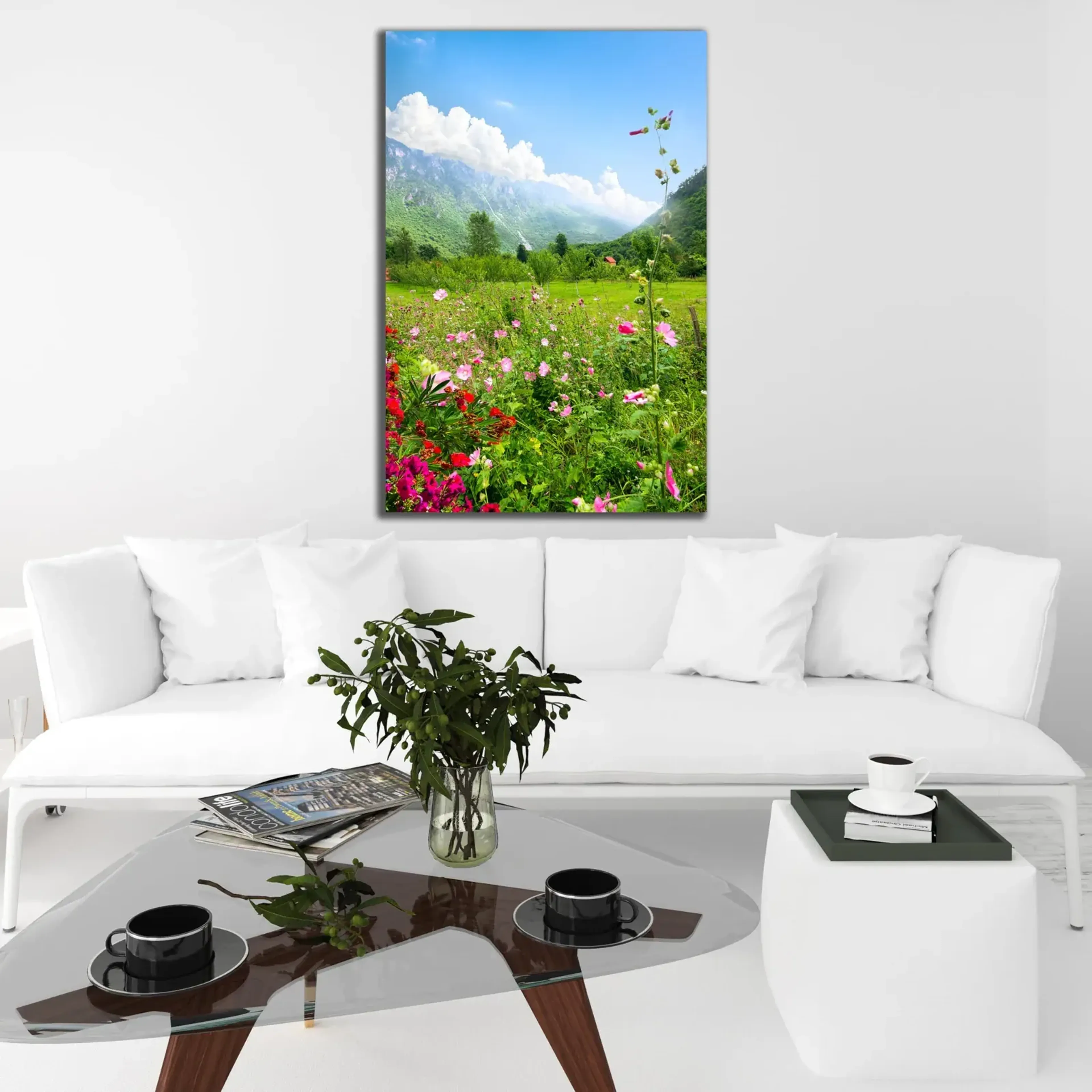 Hochformatiges Blumenwiesenmotiv mit Bergen und blauem Himmel, gezeigt über einem weißen Sofa.