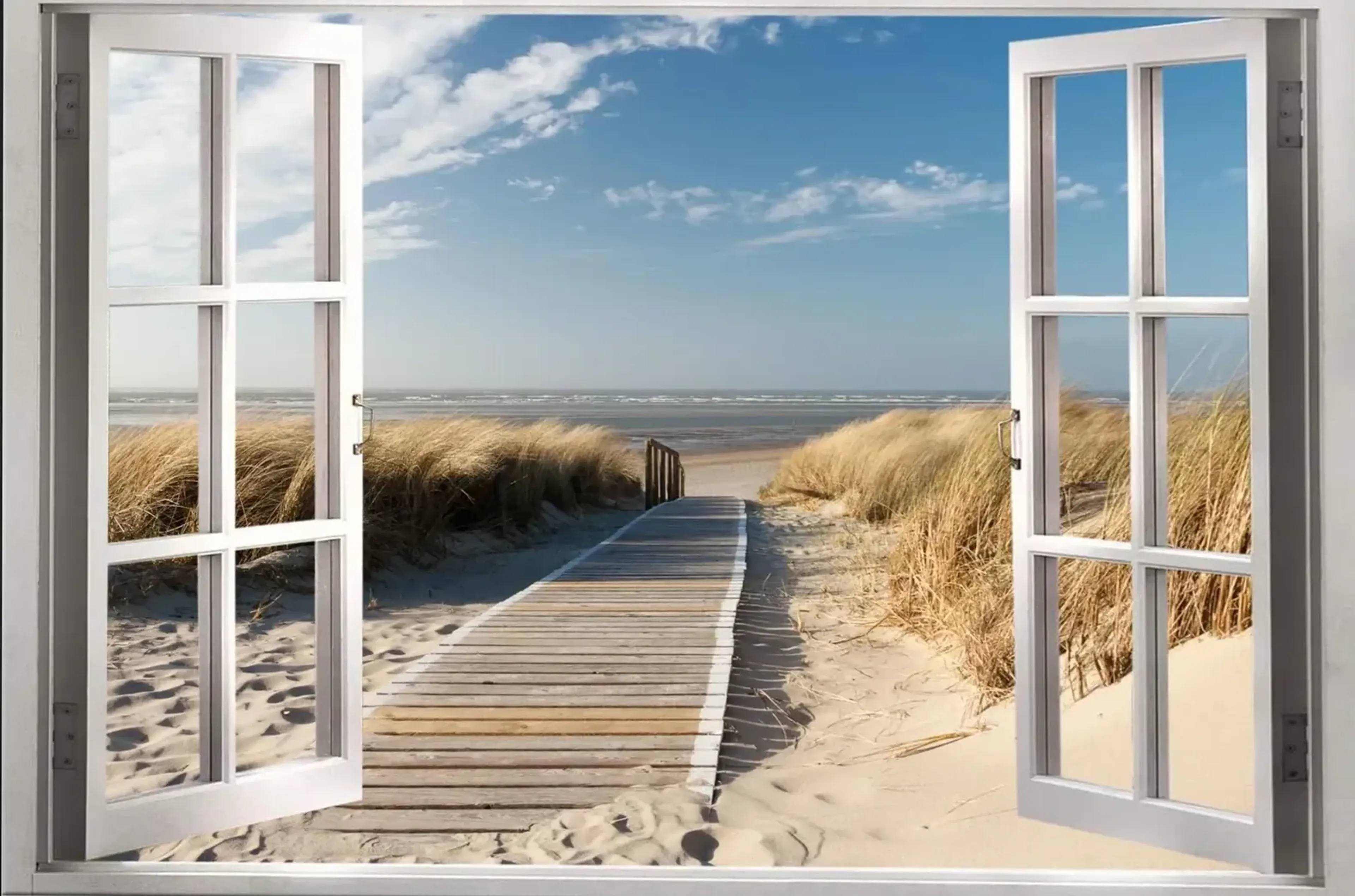 Weiße Fensterflügel rahmen einen Holzweg durch sandige Dünen mit goldbraunem Gras zum Meer unter blauem Himmel.