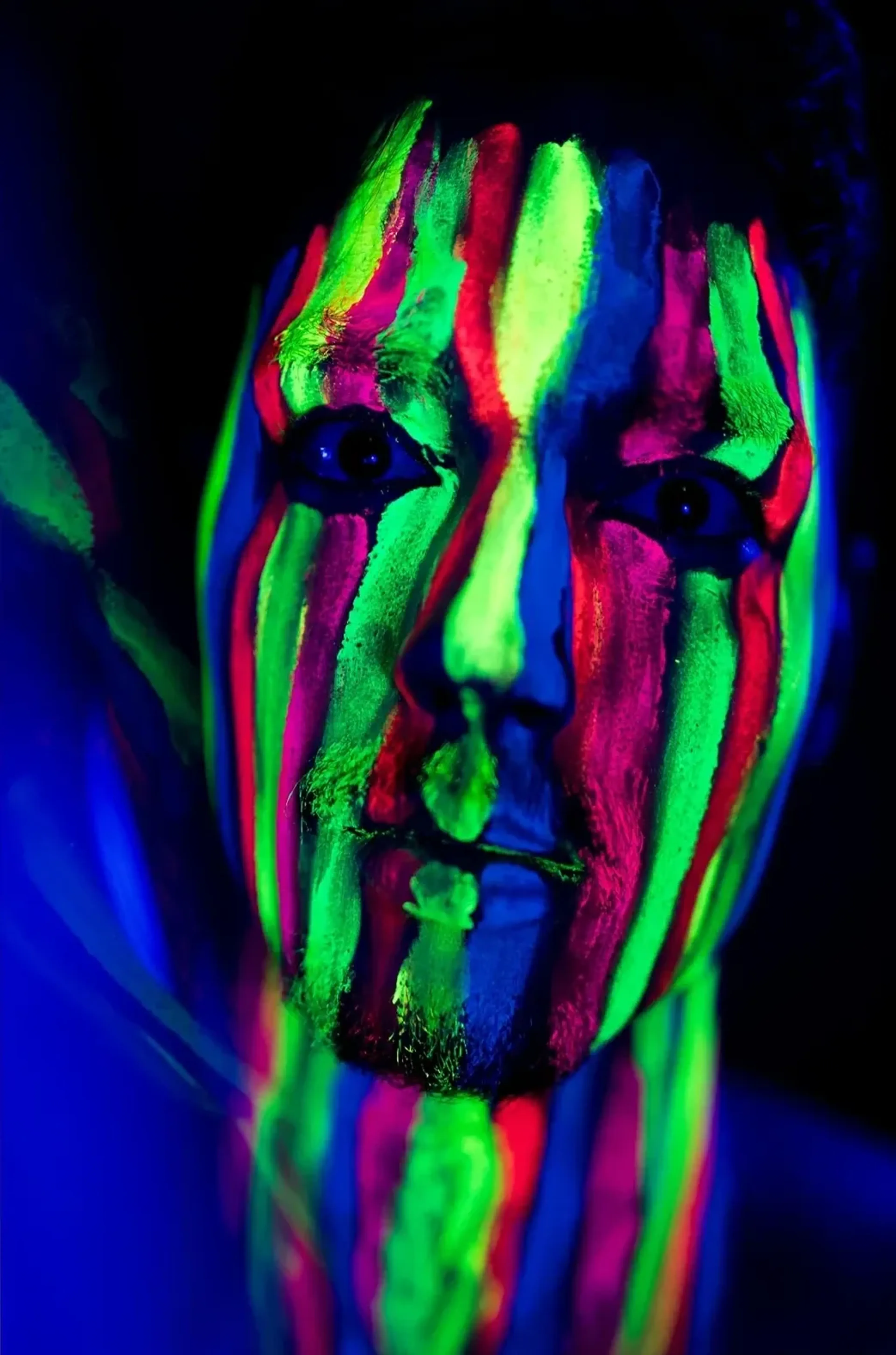 Ein frontal gezeigtes Gesicht trägt leuchtend grüne, pinke und blaue Farbstreifen vor dunklem Hintergrund.