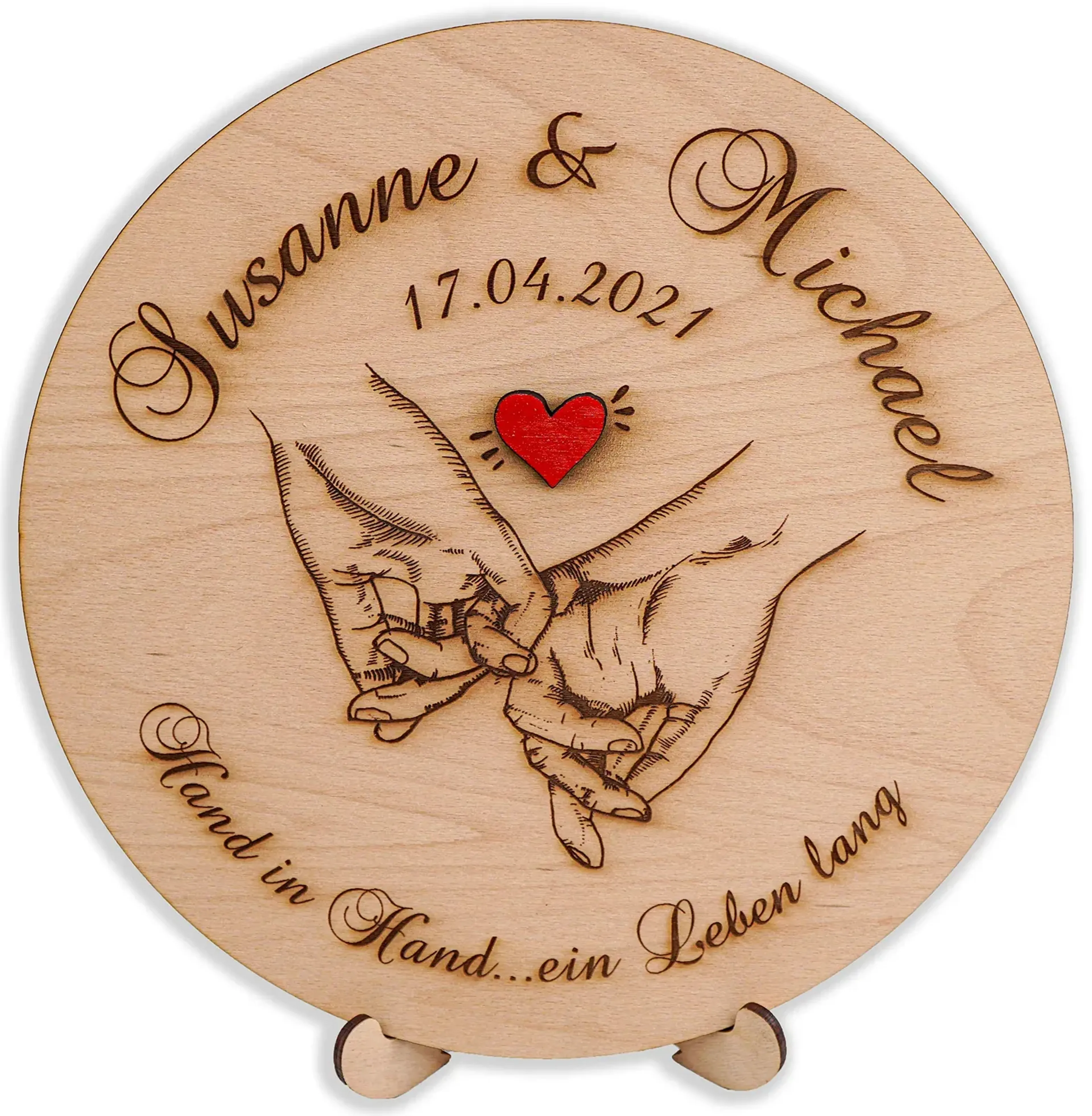 Runde Holzscheibe mit ineinandergehakten kleinen Fingern, rotem Herz sowie beispielhaften Namen, Datum und Spruch.