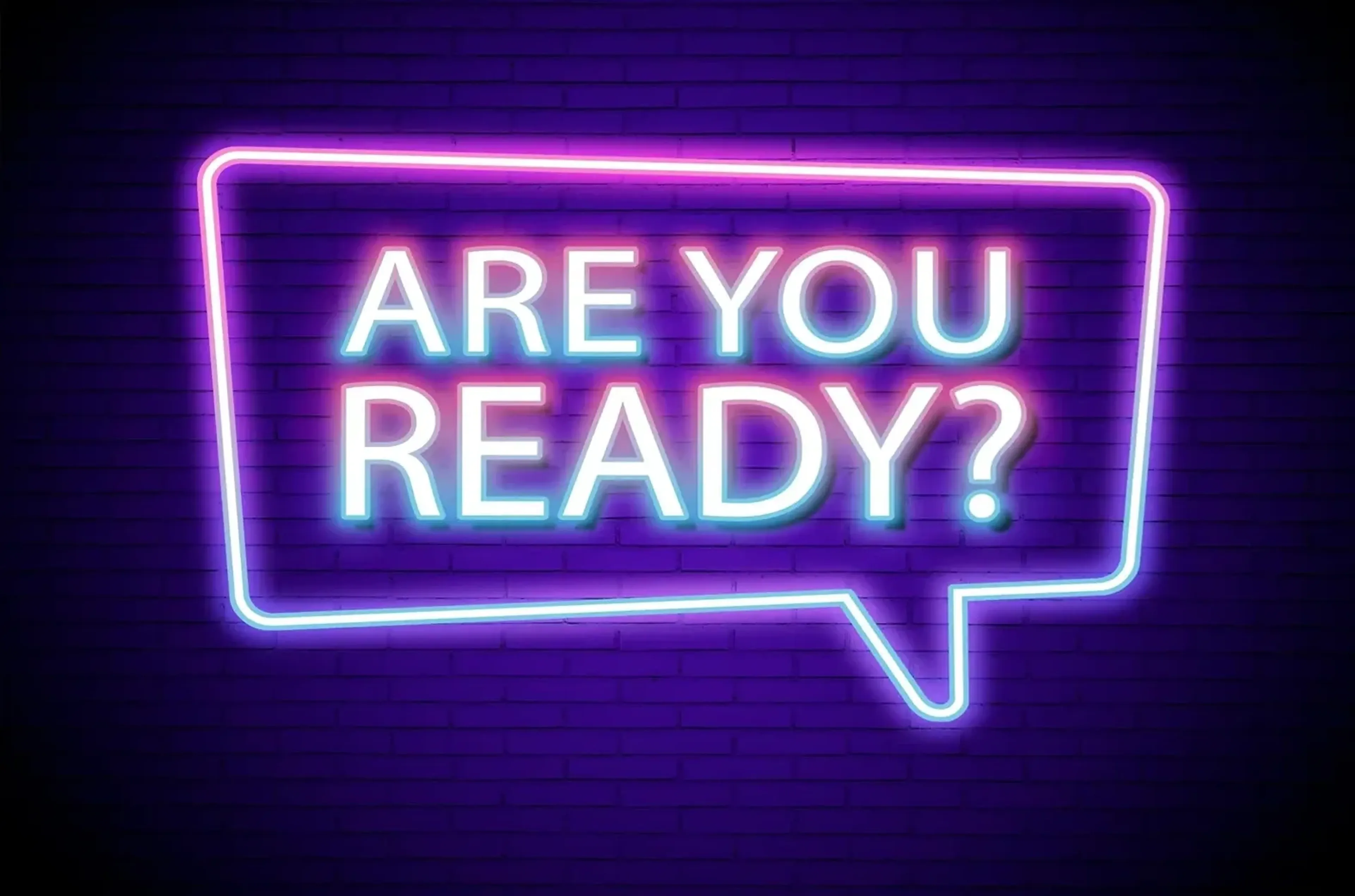 Der Schriftzug „ARE YOU READY?“ leuchtet in einer pink-blauen Sprechblase vor einer violetten Ziegelwand.